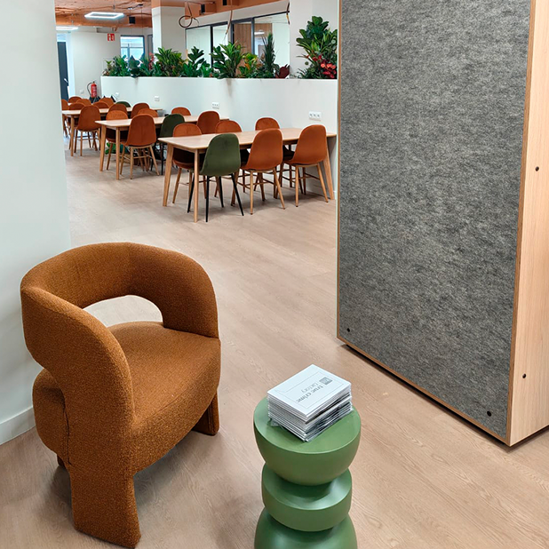 Zona común de coworking con mesas compartidas, sillas de colores y decoración con plantas naturales.