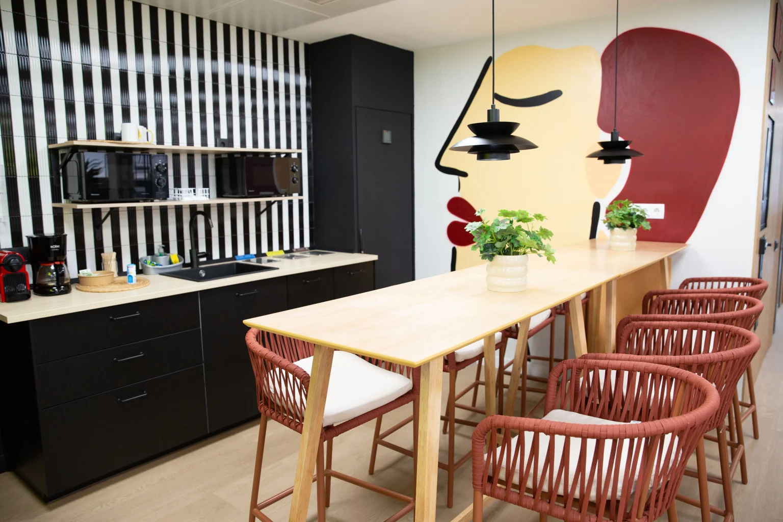 Comedor con mesa larga, sillas rojas y pared rayada