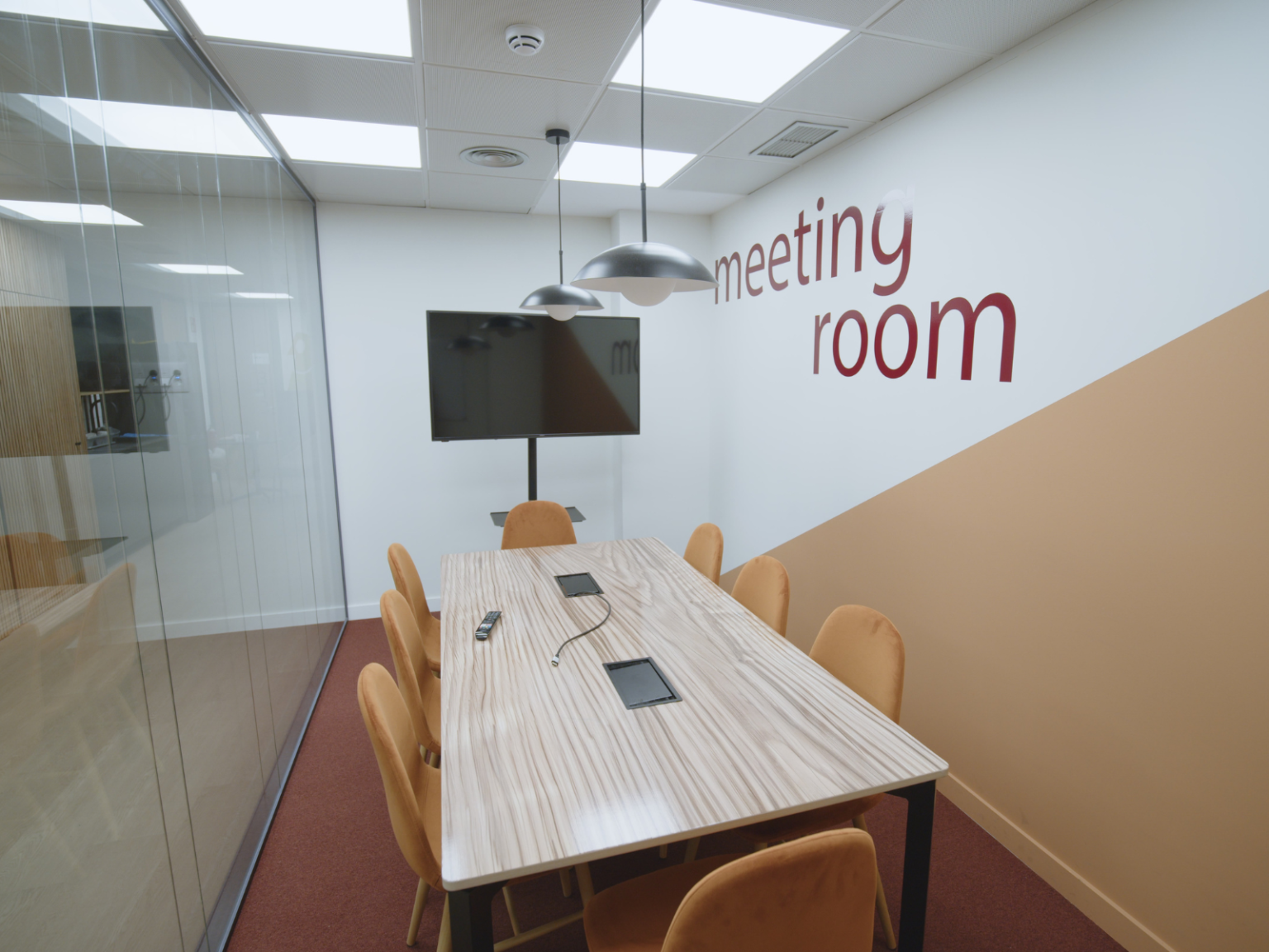 Sala de reuniones con mesa larga y pantalla